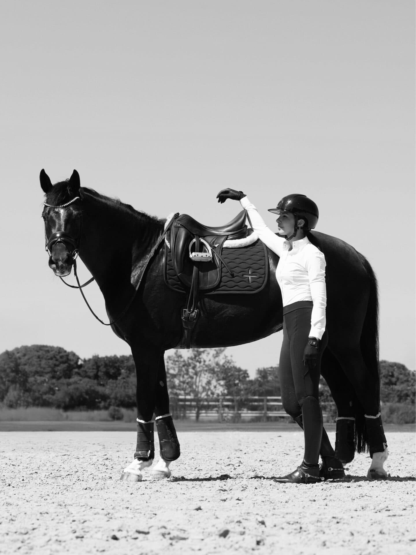 Black and white campaign photo of Grace Kay standing with her horse