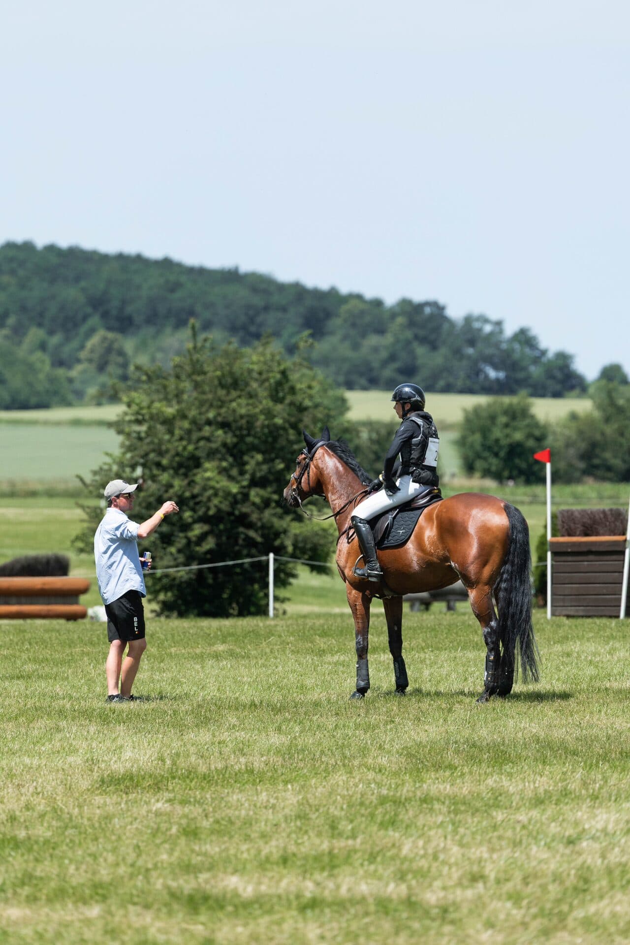 Grace Kay on her horse listening to her trainer at a cross-country course