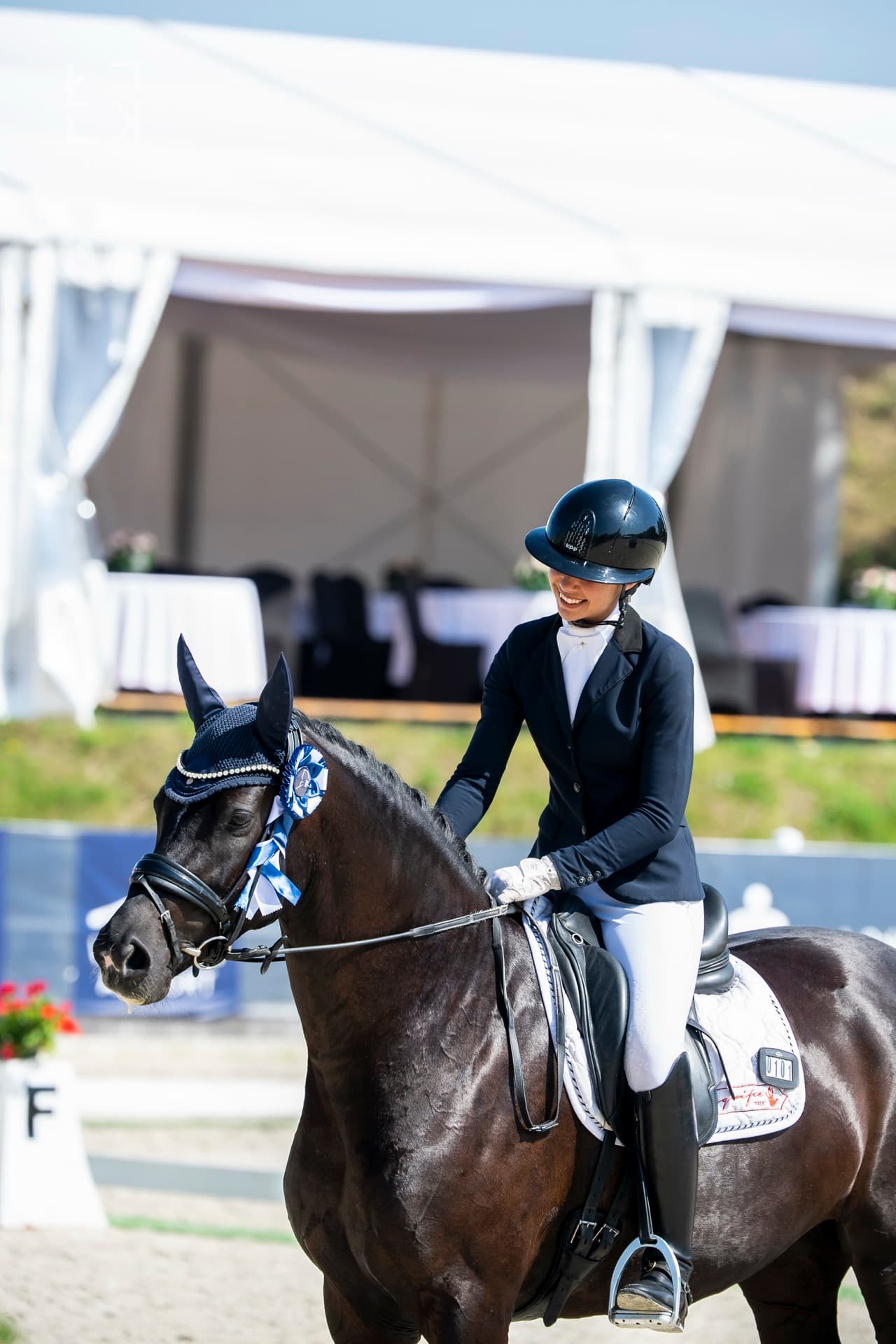 Grace Kay smiling on her horse with a rosette at a European competition